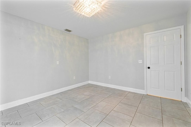 tiled spare room with a chandelier