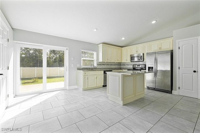 kitchen with vaulted ceiling, stainless steel appliances, backsplash, and cream cabinets