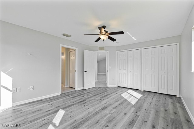 unfurnished bedroom featuring ceiling fan, light hardwood / wood-style floors, and multiple closets