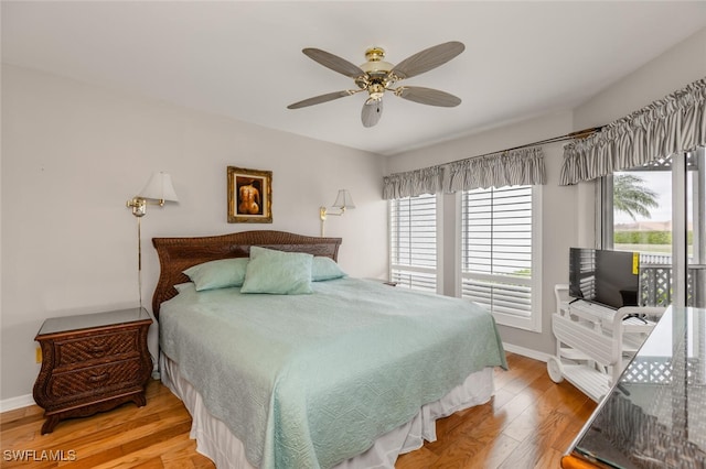 bedroom featuring hardwood / wood-style flooring, ceiling fan, and multiple windows