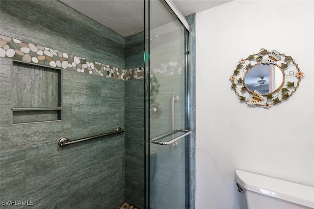 bathroom featuring toilet and a shower with door