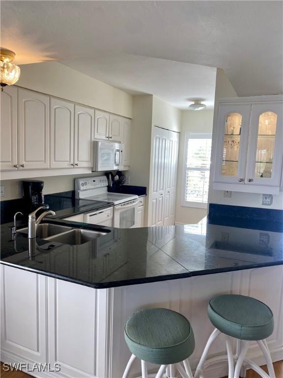 kitchen with white cabinets, white appliances, kitchen peninsula, and sink