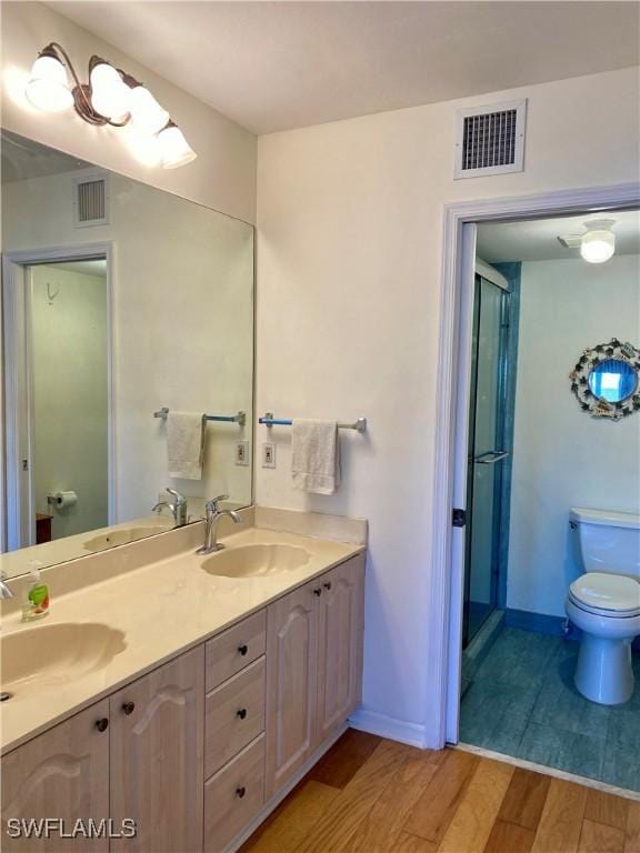 bathroom featuring hardwood / wood-style floors, vanity, toilet, and a shower with door