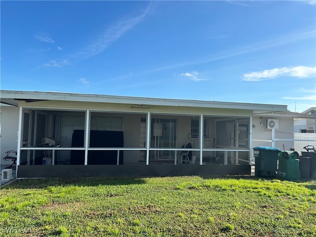 back of house featuring a sunroom and a lawn