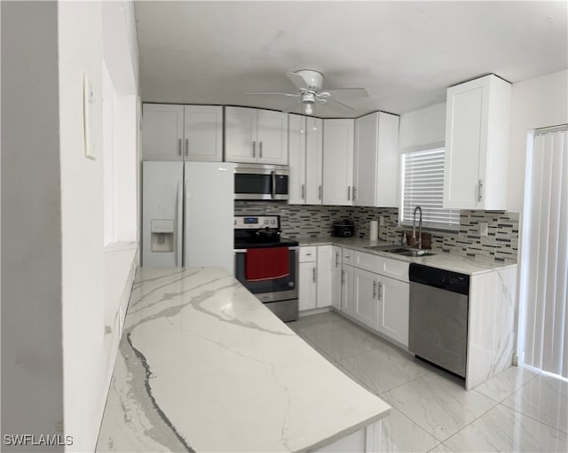 kitchen with appliances with stainless steel finishes, decorative backsplash, sink, and ceiling fan