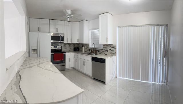 kitchen featuring ceiling fan, white cabinets, stainless steel appliances, and light stone counters