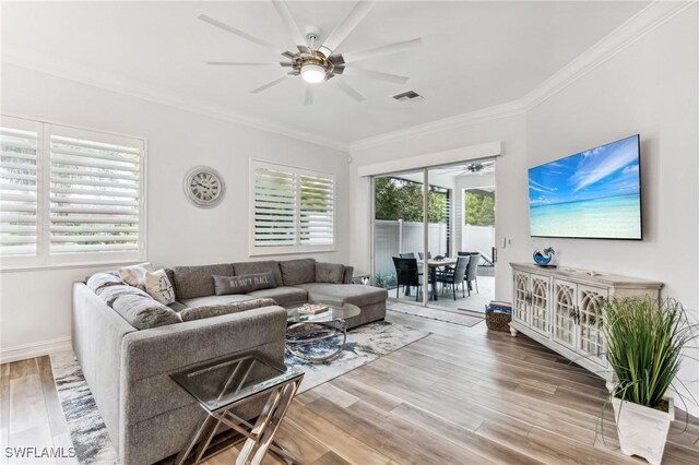 living room featuring ceiling fan, wood-type flooring, crown molding, and a wealth of natural light