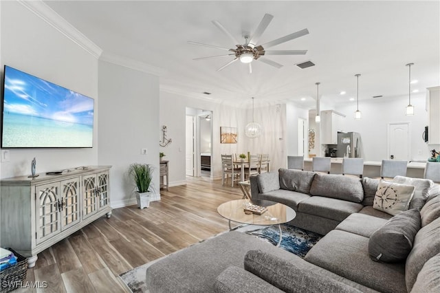 living room featuring ceiling fan, ornamental molding, and light hardwood / wood-style flooring