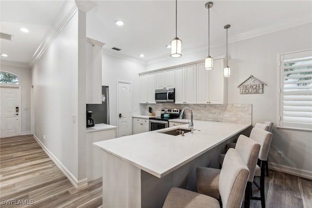 kitchen featuring a kitchen breakfast bar, kitchen peninsula, light hardwood / wood-style floors, decorative light fixtures, and appliances with stainless steel finishes