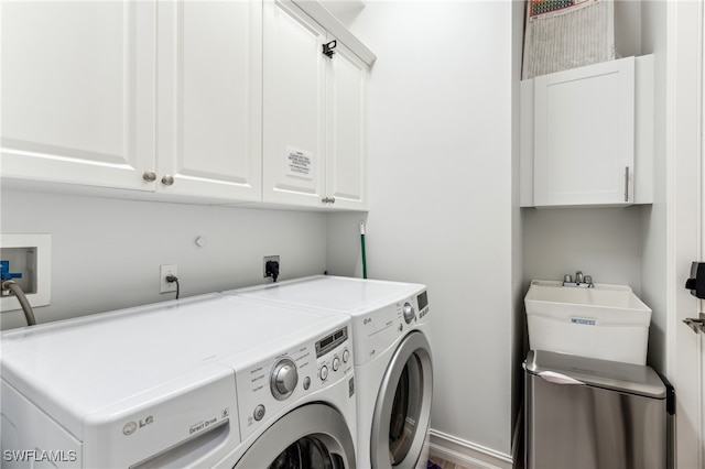 clothes washing area featuring washing machine and dryer, sink, and cabinets