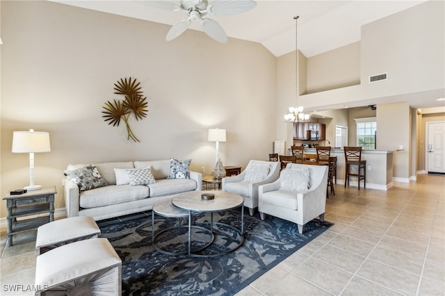 living room featuring high vaulted ceiling, ceiling fan with notable chandelier, visible vents, and light tile patterned floors