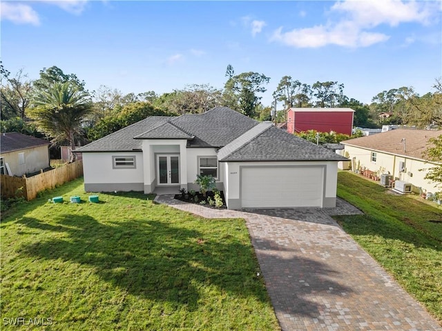 view of front of house featuring an attached garage, fence, french doors, decorative driveway, and a front lawn