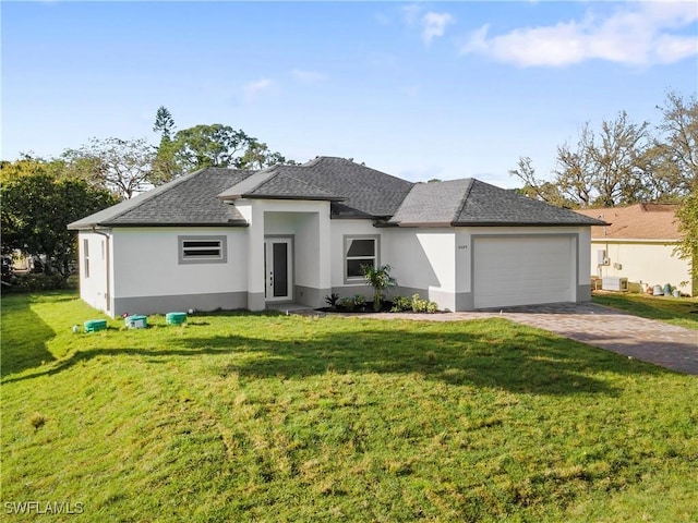 prairie-style home featuring a front lawn, decorative driveway, an attached garage, and stucco siding