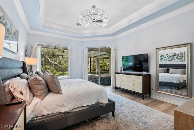 bedroom with access to outside, a tray ceiling, crown molding, light hardwood / wood-style flooring, and a notable chandelier