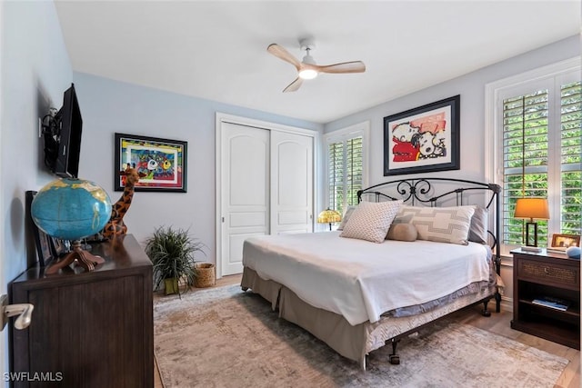 bedroom featuring multiple windows, ceiling fan, a closet, and light hardwood / wood-style flooring