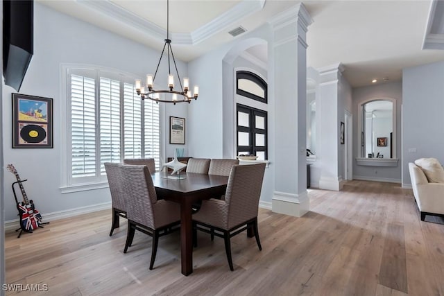 dining room with a tray ceiling, an inviting chandelier, crown molding, and light hardwood / wood-style flooring