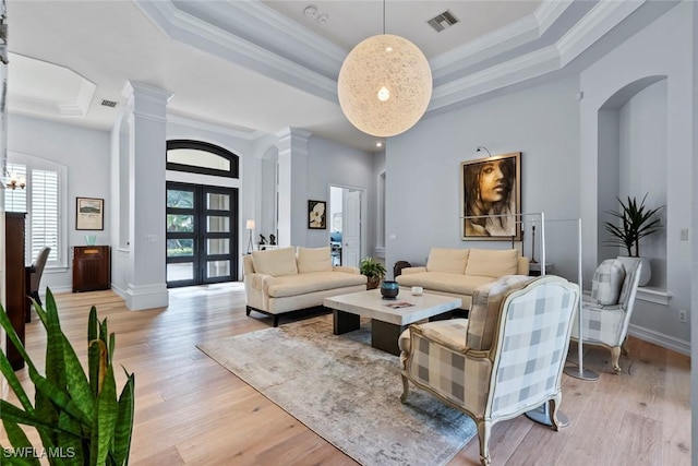 living room featuring french doors, a raised ceiling, crown molding, a towering ceiling, and light hardwood / wood-style floors