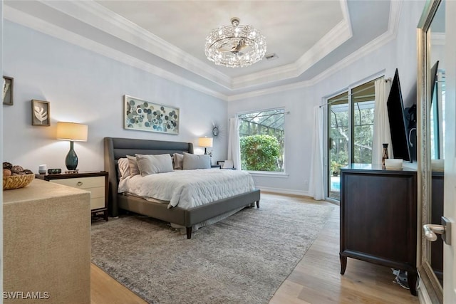 bedroom with an inviting chandelier, access to outside, light hardwood / wood-style flooring, and a tray ceiling