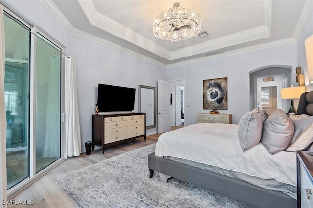 bedroom with hardwood / wood-style floors, an inviting chandelier, a tray ceiling, and multiple windows