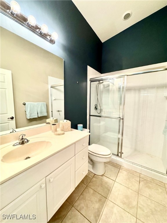 bathroom with tile patterned flooring, vanity, toilet, and a shower with door