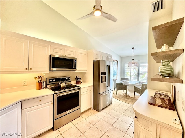 kitchen with appliances with stainless steel finishes, vaulted ceiling, light tile patterned floors, decorative light fixtures, and white cabinetry