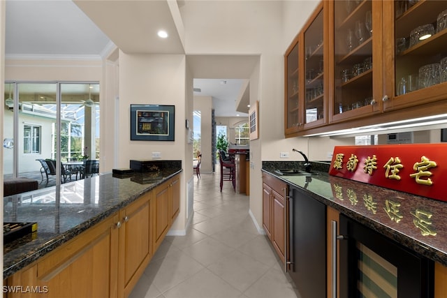 kitchen with dark stone countertops, wine cooler, crown molding, and sink