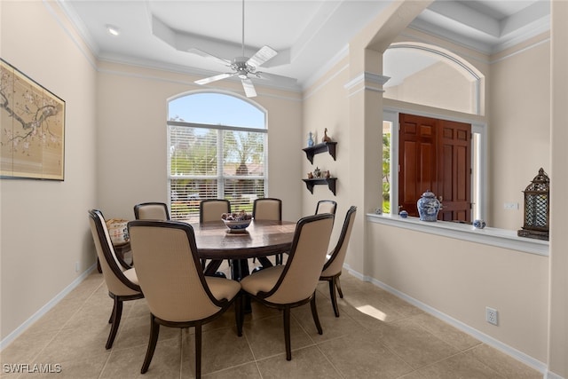 dining space featuring ceiling fan, a raised ceiling, light tile patterned floors, and crown molding