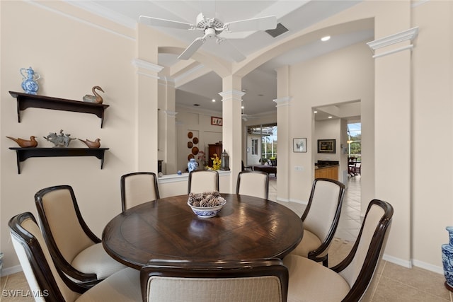 tiled dining space featuring decorative columns, ceiling fan, and crown molding