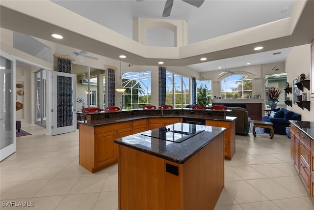 kitchen featuring dark stone countertops, a center island, light tile patterned floors, and black electric stovetop