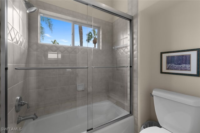 bathroom with toilet and combined bath / shower with glass door