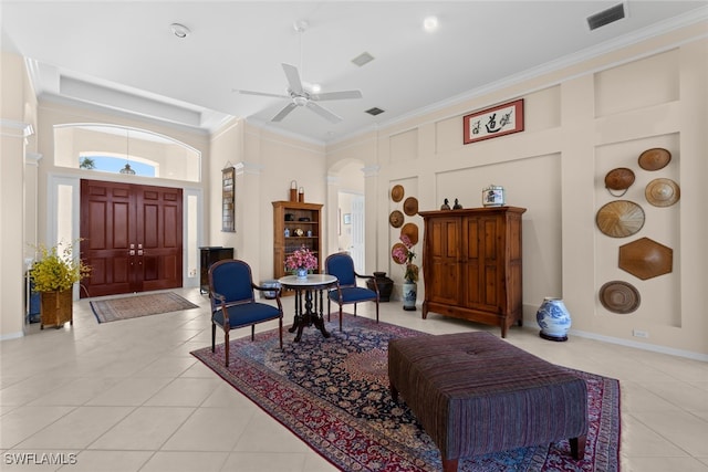 living area with ceiling fan, light tile patterned floors, a high ceiling, and ornamental molding