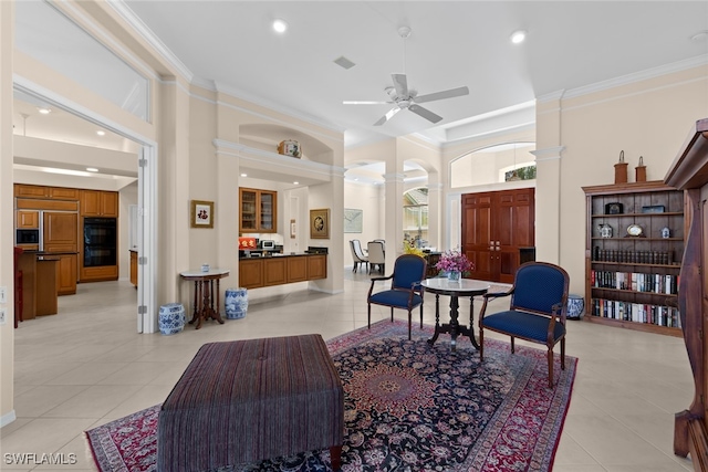 living area with ornate columns, ceiling fan, light tile patterned floors, and ornamental molding