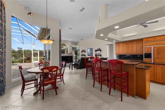 kitchen featuring backsplash, ceiling fan, dark stone countertops, paneled fridge, and a breakfast bar area