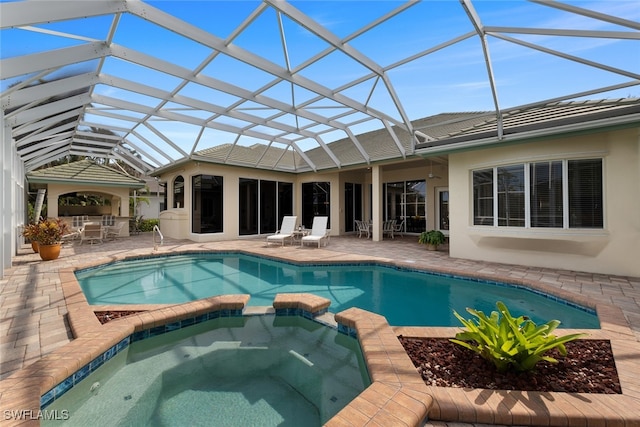 view of pool featuring glass enclosure, an in ground hot tub, and a patio area