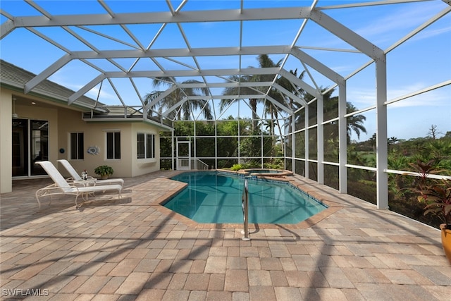 view of swimming pool with glass enclosure, an in ground hot tub, and a patio