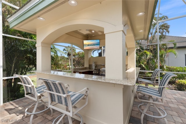 view of patio with glass enclosure and an outdoor bar