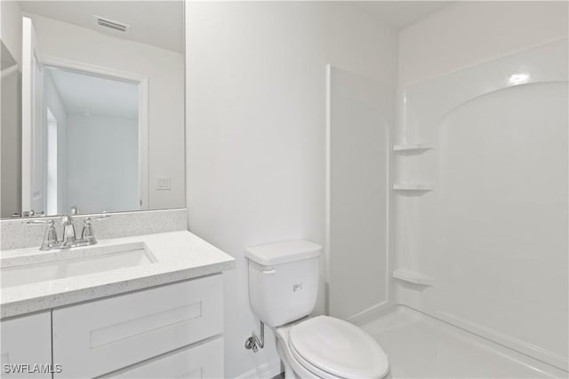 bathroom featuring vanity, a shower, and toilet