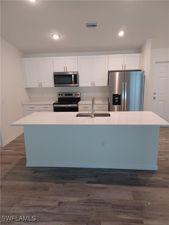 kitchen with sink, appliances with stainless steel finishes, white cabinetry, a kitchen island with sink, and dark hardwood / wood-style floors