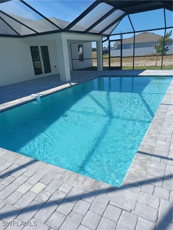 view of swimming pool with a patio area and glass enclosure