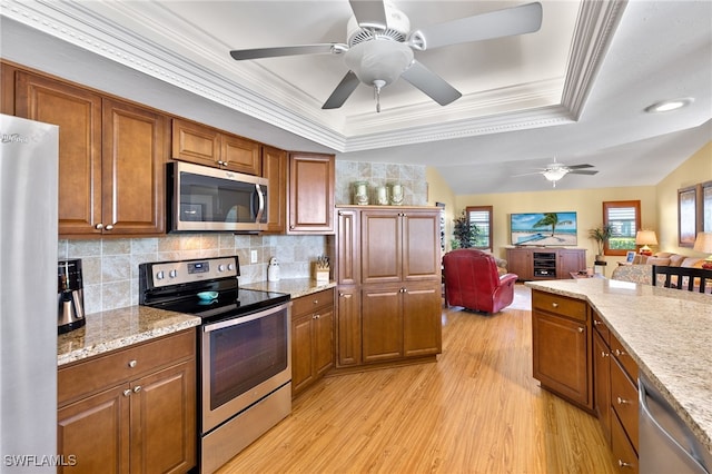 kitchen featuring a healthy amount of sunlight, appliances with stainless steel finishes, light hardwood / wood-style floors, and decorative backsplash