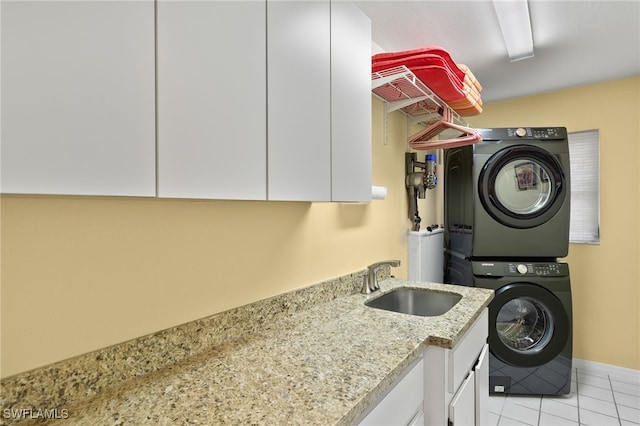 laundry room featuring stacked washer / dryer, sink, light tile patterned floors, and cabinets