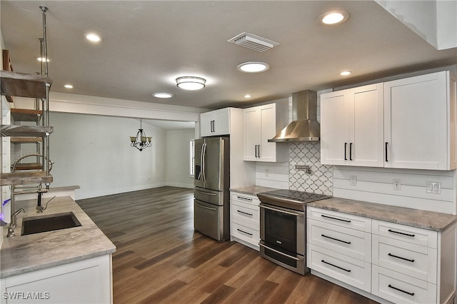 kitchen featuring wall chimney exhaust hood, white cabinetry, hanging light fixtures, and appliances with stainless steel finishes