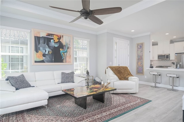 living room featuring ornamental molding, light hardwood / wood-style floors, and ceiling fan