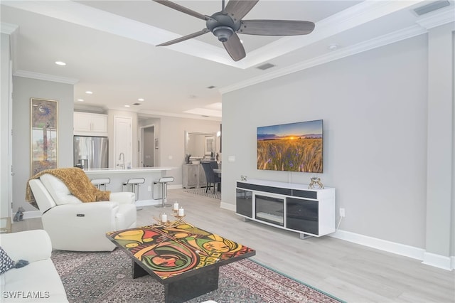 living room featuring ornamental molding, sink, light wood-type flooring, and ceiling fan