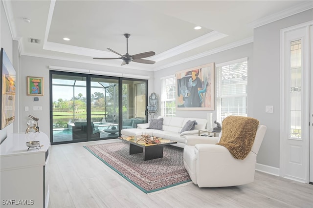 living room with ceiling fan, a healthy amount of sunlight, ornamental molding, and light wood-type flooring