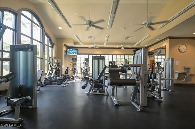 gym with a wealth of natural light, a towering ceiling, and ceiling fan