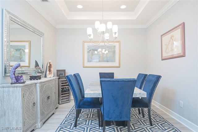 dining room with crown molding, a notable chandelier, light hardwood / wood-style flooring, and a raised ceiling