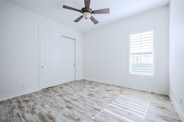 unfurnished bedroom featuring ceiling fan, a closet, and light wood-type flooring