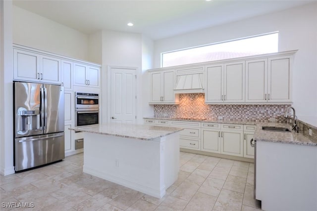 kitchen with sink, custom exhaust hood, appliances with stainless steel finishes, a kitchen island, and backsplash