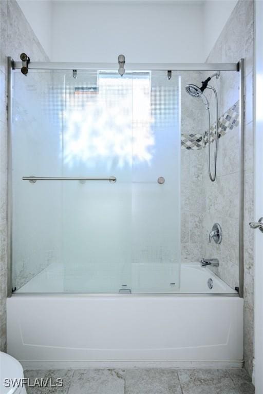 bathroom with toilet and bath / shower combo with glass door